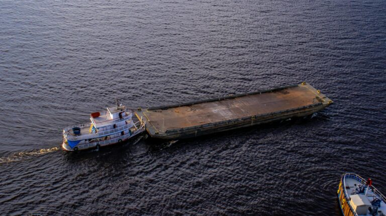 Aerial shot of a tugboat towing a barge on the river in Manaus, Brasil.