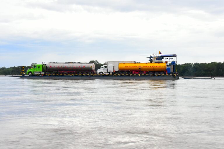 Tanker trucks on a barge navigate the Amazon River. Efficient waterway logistics in Brazil.